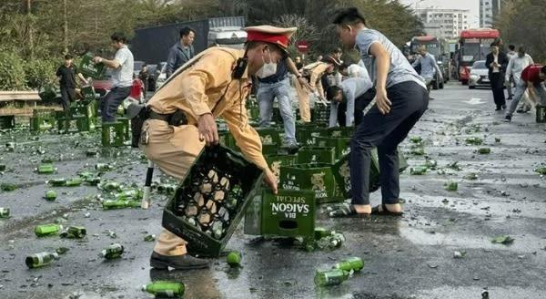Cảnh sát giao thông cùng người dân thu dọn hàng trăm thùng bia rơi xuống đường