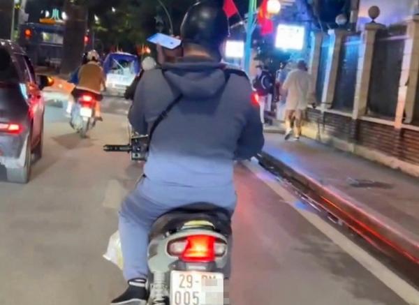 Một thanh niên sử dụng điện thoại khi điều khiển mô tô bị phạt tiền và trừ 4 điểm giấy phép lái xe